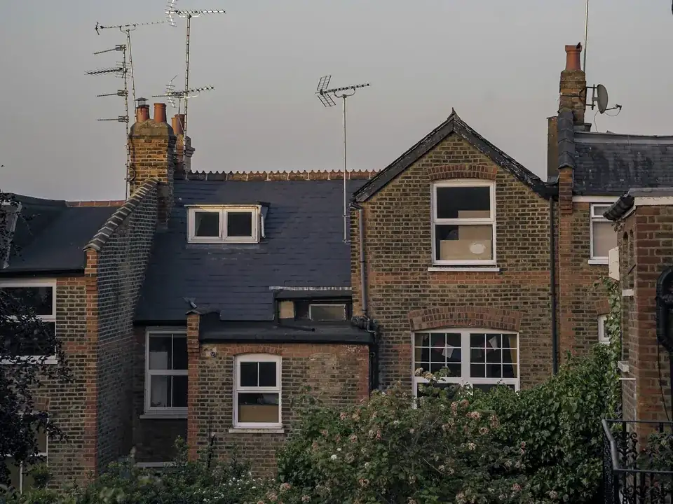 Rear view of brick terraced houses in London with slate roofs and chimney stacks along the shared roofline