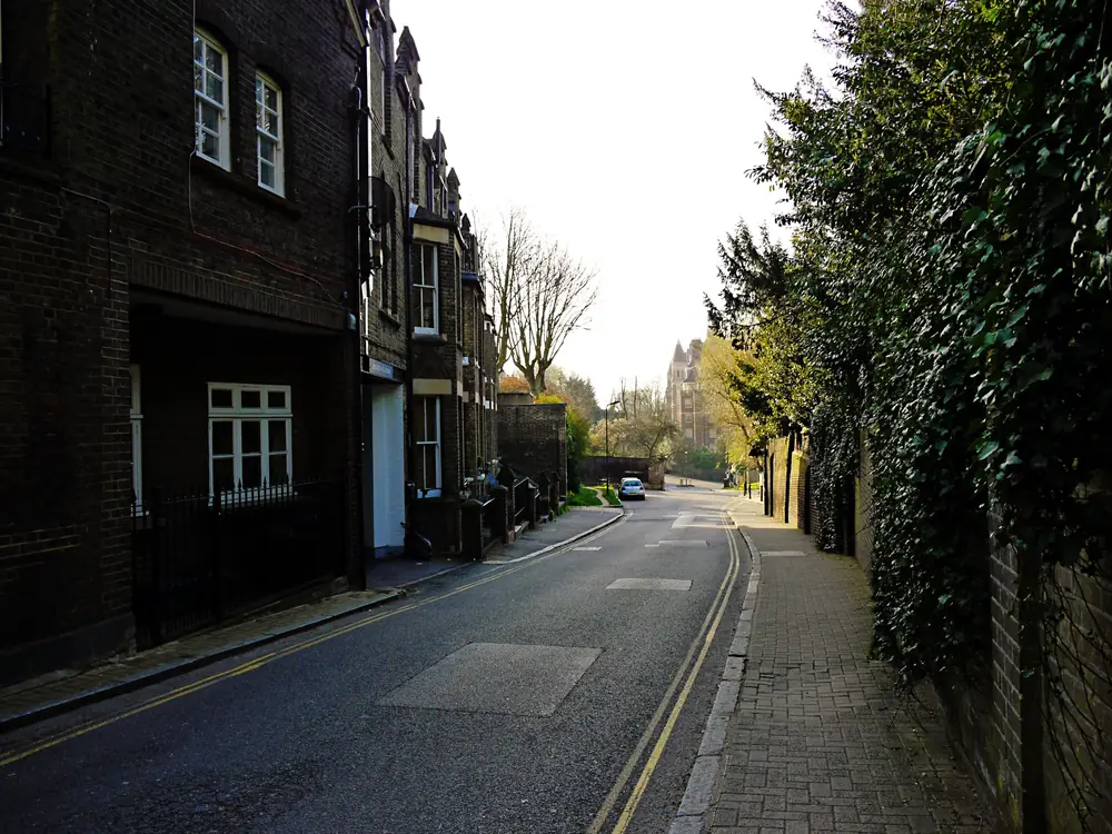 Hampstead lane between dark brick period houses and ivy-covered garden walls