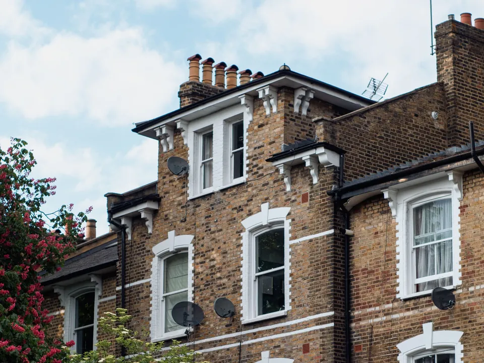 Upper floors of a large yellow-brick Victorian house in London with chimney pots
