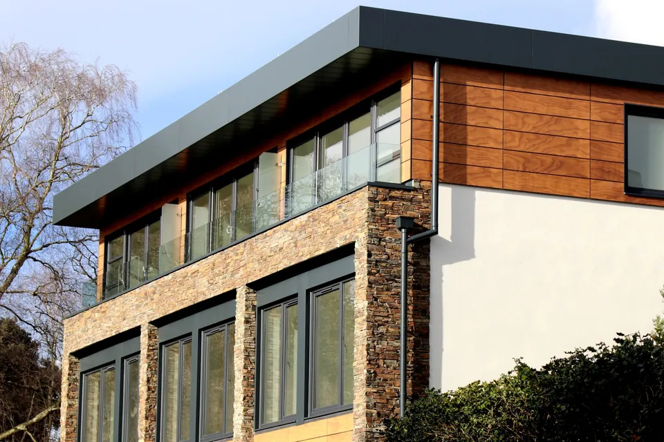 Contemporary house with stone and timber cladding, white render and large dark-framed windows