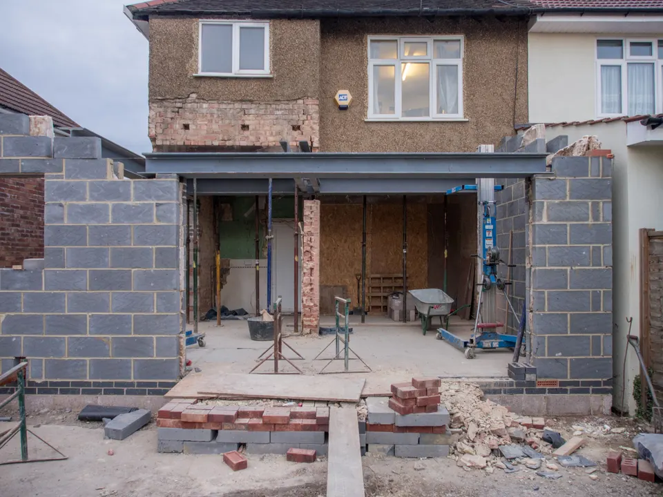 Brick house being extended, with a wide new opening supported over the ground floor